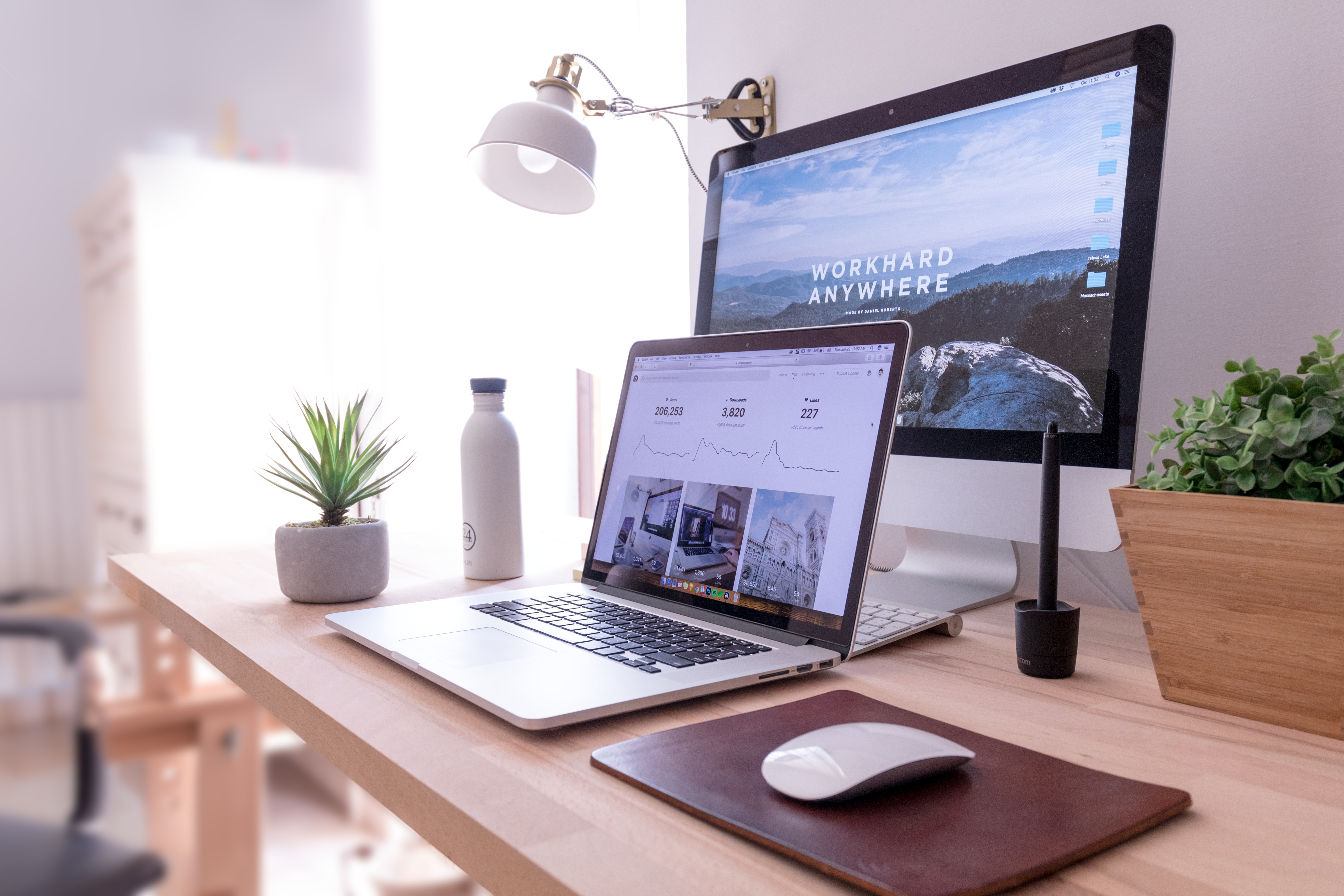 MacBook Pro sur une table à côté d'un iMac blanc et d'une souris Magic Mouse